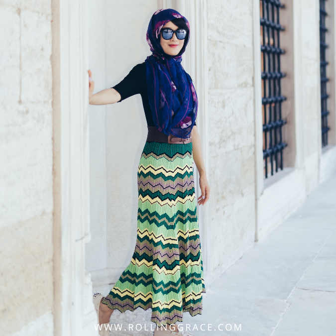 Woman in hijab and patterned maxi skirt standing at a white heritage building in Malaysia