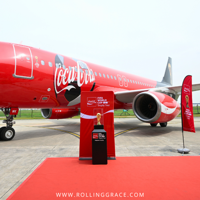 Original FIFA World Cup Trophy displayed on the tarmac beside a Coca-Cola aircraft during the Trophy Tour in Malaysia
