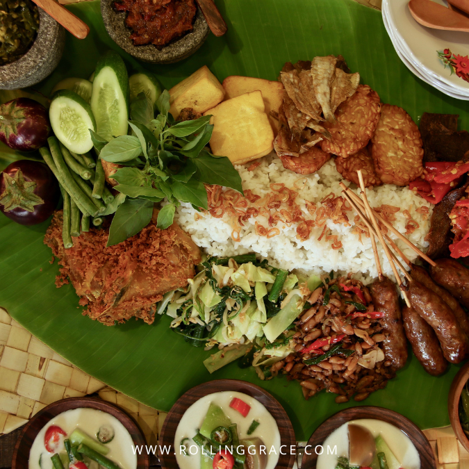 Rijsttafel Bali is a rice table spread with multiple small dishes of meat, sambal, sate and vegetables on a banana leaf
