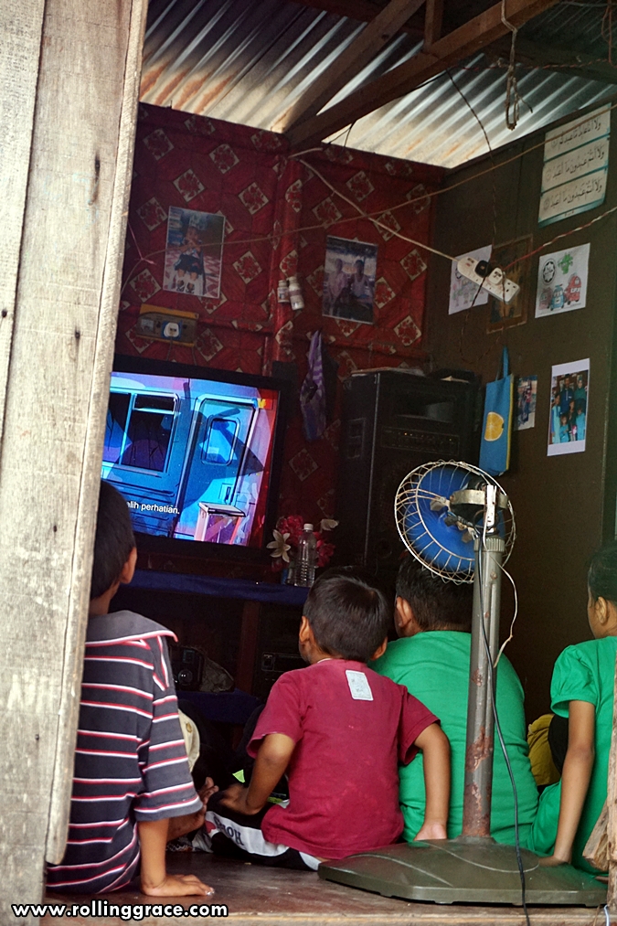 Bajau Laut children watching television inside a home at Kampung Mabul, Pulau Mabul, Sabah