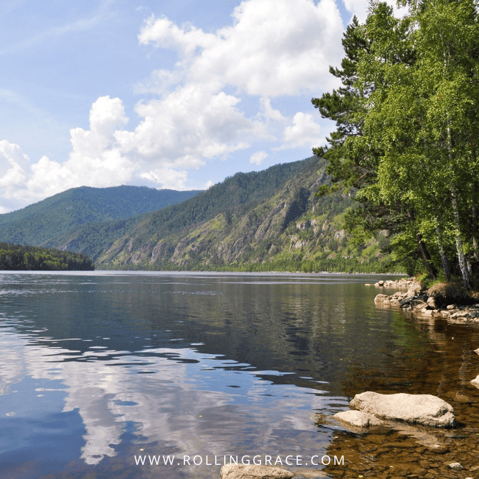 Calm lake surrounded by forested mountains in Emeishan, Sichuan China