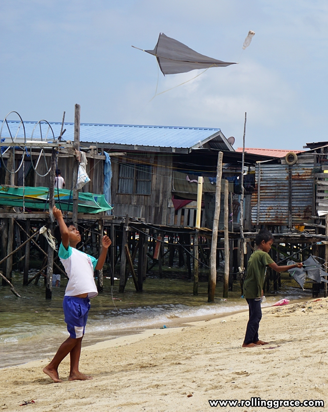 Bajau Laut child flying a kite on the beach at Kampung Mabul, Pulau Mabul, Sabah