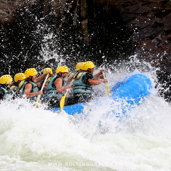 Group of rafters in orange helmets and life jackets on a Malaysian river in Perak