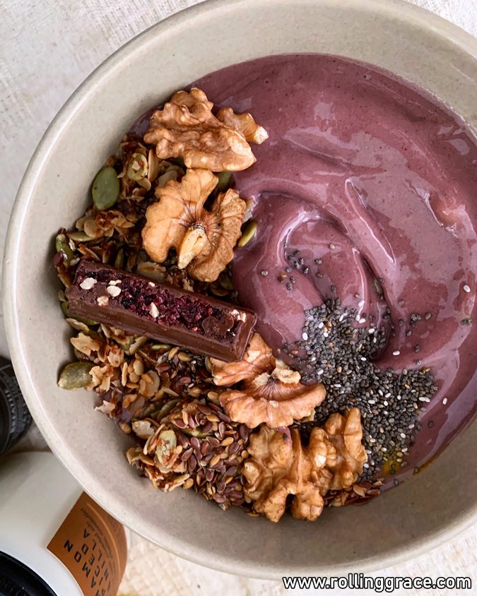 Purple acai smoothie bowl topped with granola, fresh berries, and seeds