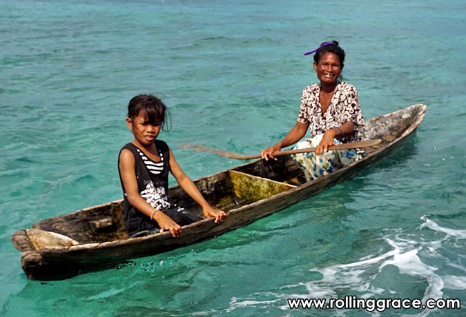 Bajau Laut children rowing a wooden boat on turquoise sea Semporna Sabah Malaysia