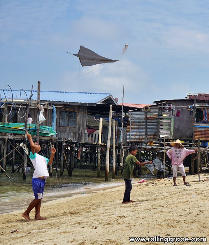 Boy flying a kite in front of Bajau Laut stilt houses at Pulau Mabul Sabah Malaysia
