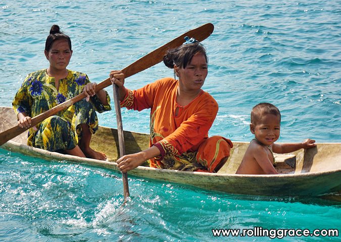 Two Bajau Laut women rowing a wooden boat on the Celebes Sea Sabah Malaysia