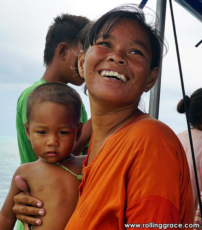 Young smiling Bajau Laut mother holding baby on wooden boat Pulau Mabul Sabah