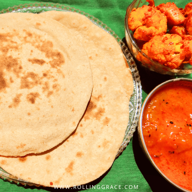 Stack of freshly made chapati on a banana leaf served with tomato curry and gobi (cauliflower) on the side