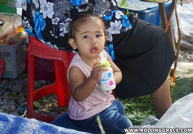 A young child eating a snack at Nat Pokok Getah morning market in Arau, Perlis