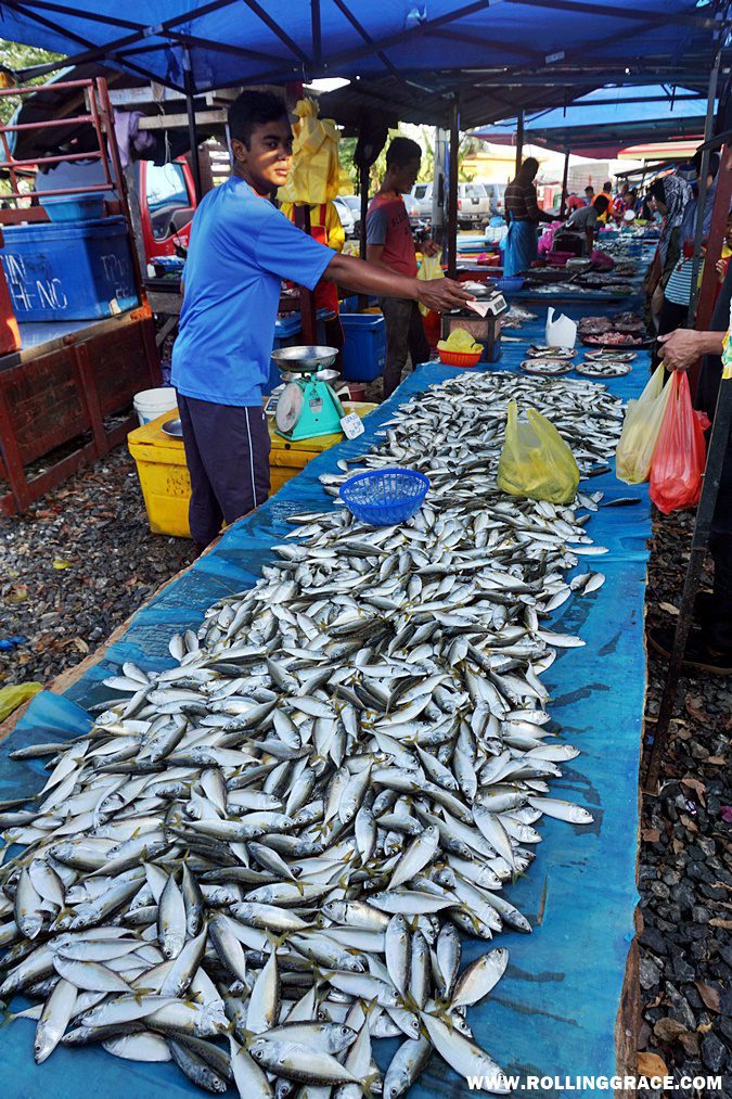 A vendor in a white cap arranging fresh fish at the wet market section of Nat Pokok Getah in Perlis