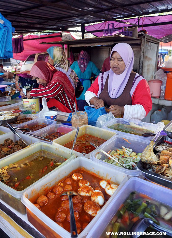 Economy rice stall with trays of curries, sambals, and fried dishes served by a vendor at Nat Pokok Getah in Perlis