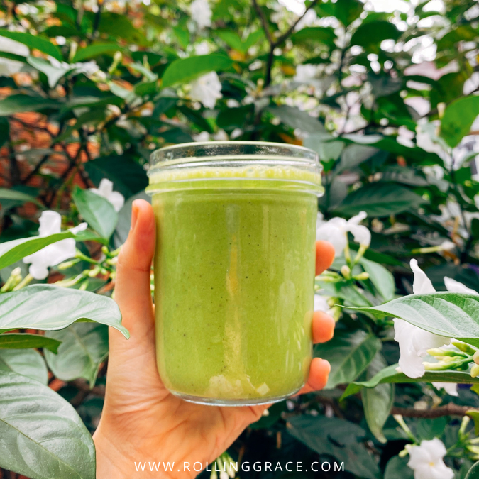Bright green vegan smoothie made with spinach and banana held in a glass outdoors