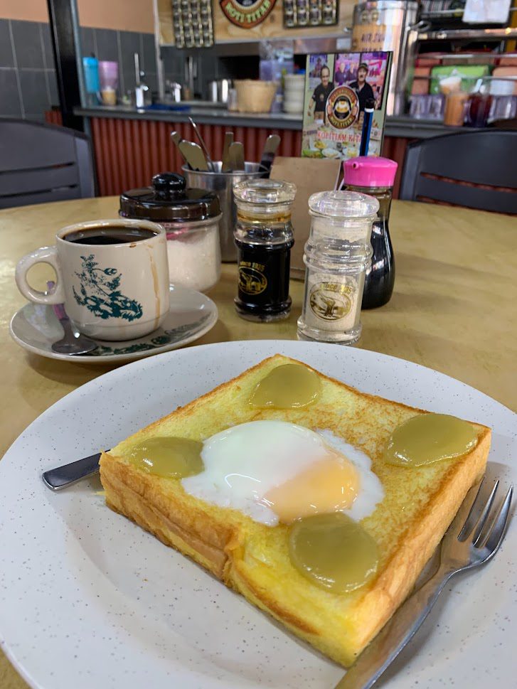 Roti titab with half boiled egg and kaya on a plate at Kopitiam Kita Kota Bharu Kelantan