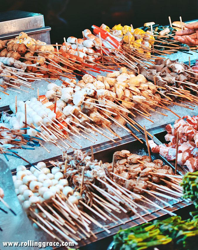 Rows of lok lok skewers displayed at a Penang street food stall at night, ready to be boiled or grilled