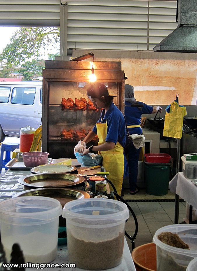 A vendor grilling tongkeng and marinated meats over an open charcoal flame at the outdoor section of Gadong Night Market in Brunei