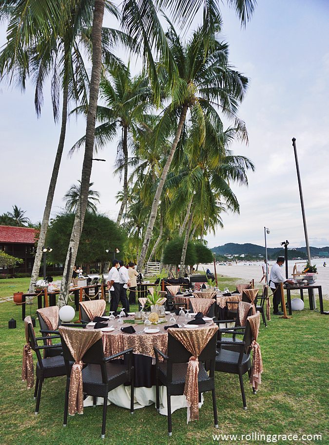 Beachfront dining table set up on Pantai Cenang at sunset with views over the Andaman Sea in Langkawi