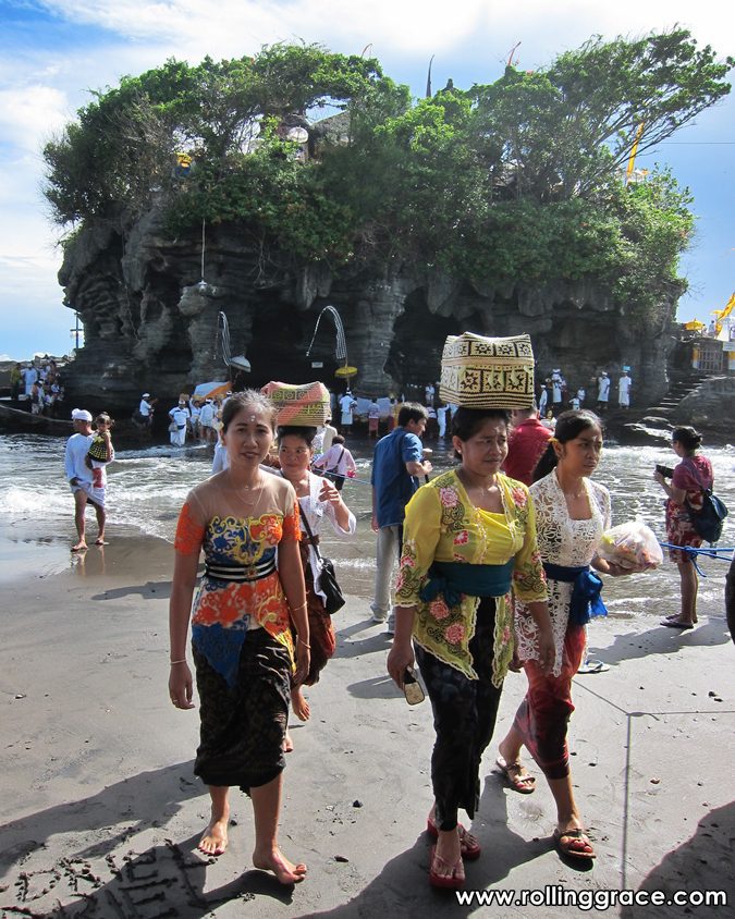 Procession of Balinese women walking on the beach with ceremonial offerings