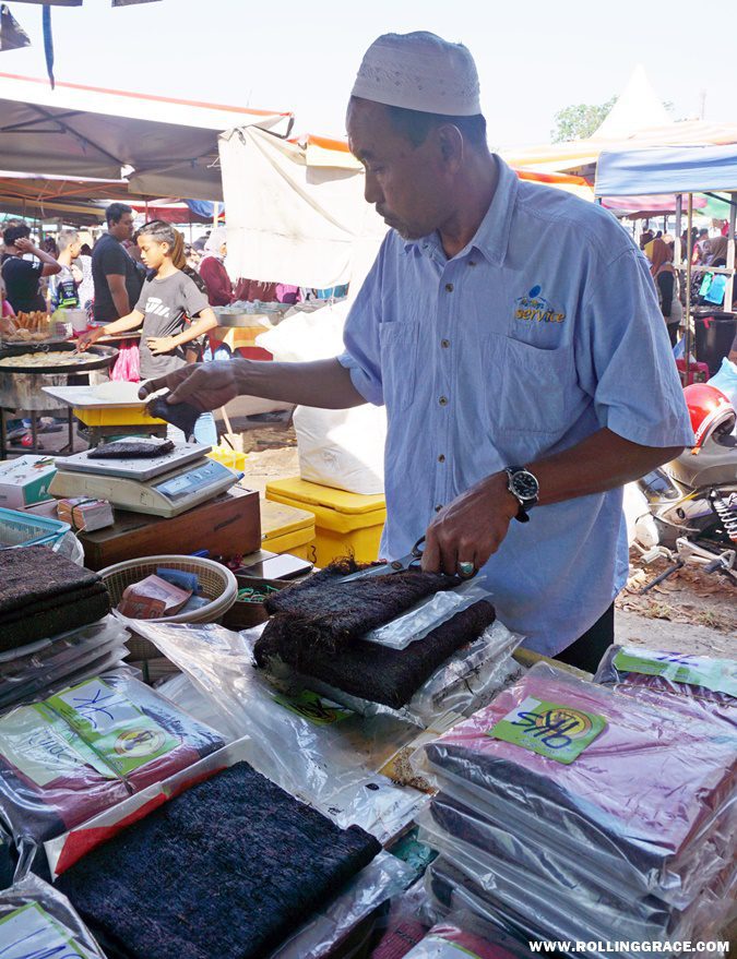A vendor cutting and preparing locally produced tobacco sheets for sale at Nat Pokok Getah morning market in Perlis