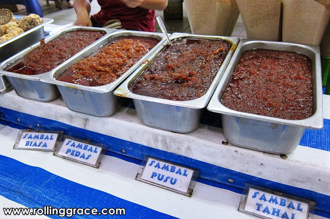 Trays of different sambal varieties with handwritten labels including sambal pedas, sambal pusu, and sambal tahai at Gadong Night Market in Brunei