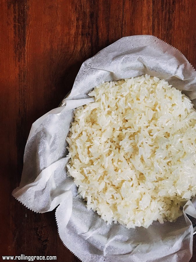 Overhead view of freshly steamed glutinous rice spread on a muslin cloth inside a steamer