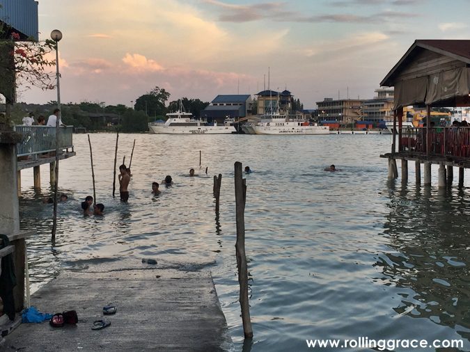 Wide river view at Bagan Hailam Port Klang at sunset with stilt houses and children swimming in the Klang River.