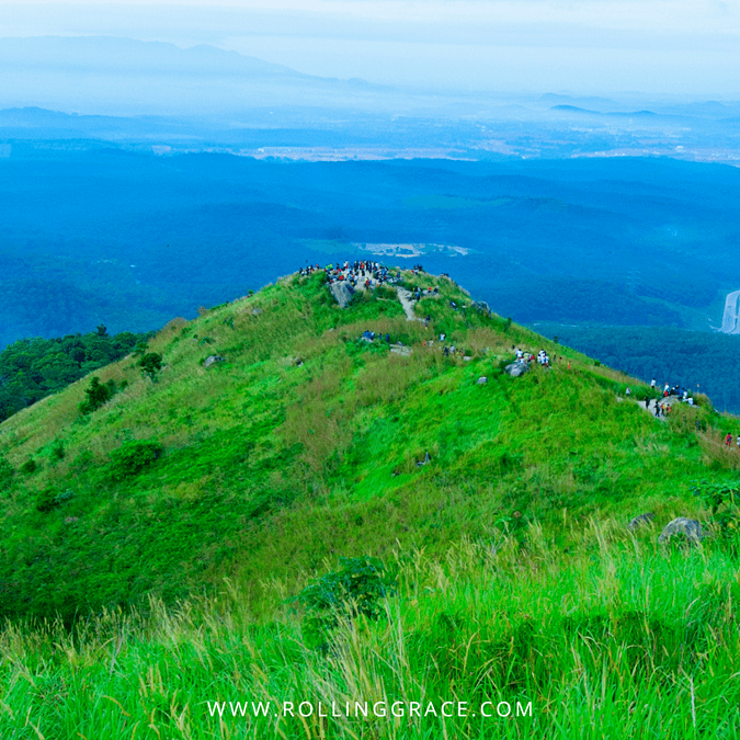 Aerial view of the green lalang-covered peaks of Broga Hill with hikers gathered at the summit in Semenyih