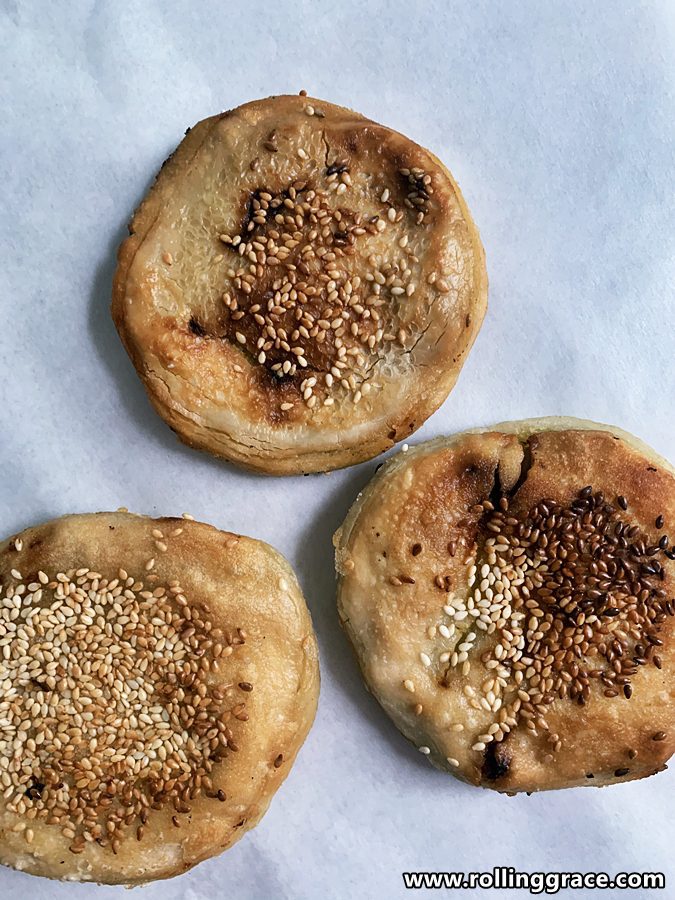 5 Tips to Make the Perfect Chinese Sweet Potato Pancakes 7 Three golden Chinese sweet potato pancakes with sesame seeds on baking paper, close overhead shot.