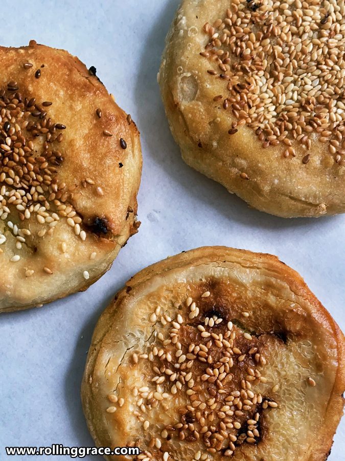 5 Tips to Make the Perfect Chinese Sweet Potato Pancakes 1 Three golden Chinese sweet potato pancakes with sesame seed coating on white baking paper, portrait orientation