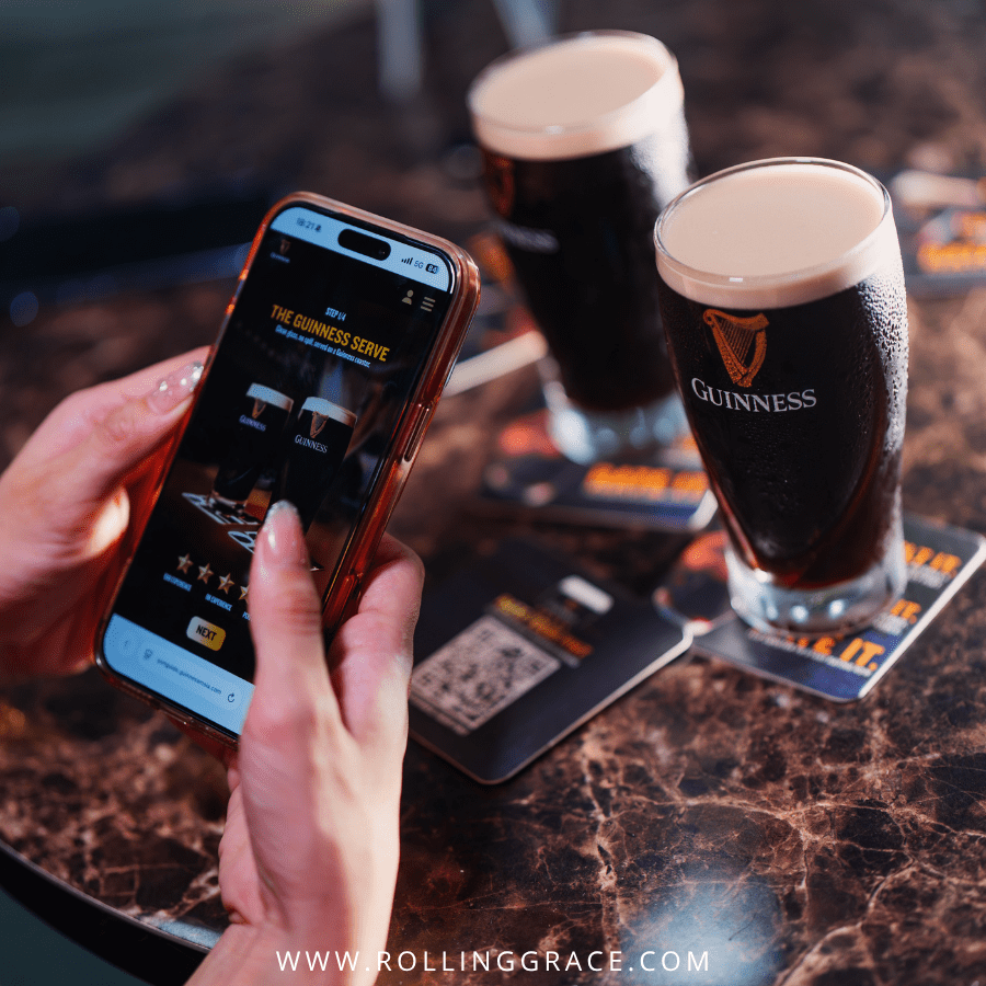 Hand holding a phone with the Rate Your Pint microsite next to a Guinness Draught pint, Malaysia