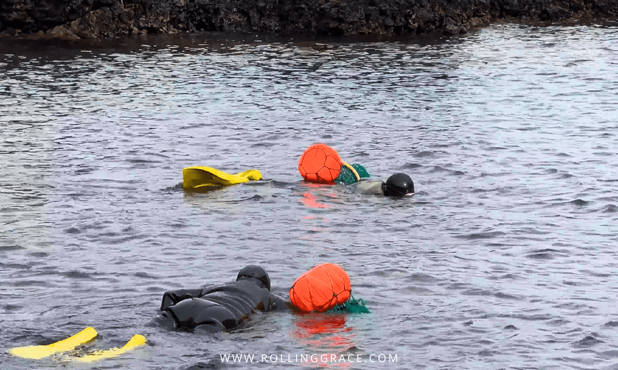 Two haenyeo divers standing on the rocky shore of Jeju Island preparing their equipment before diving, South Korea.