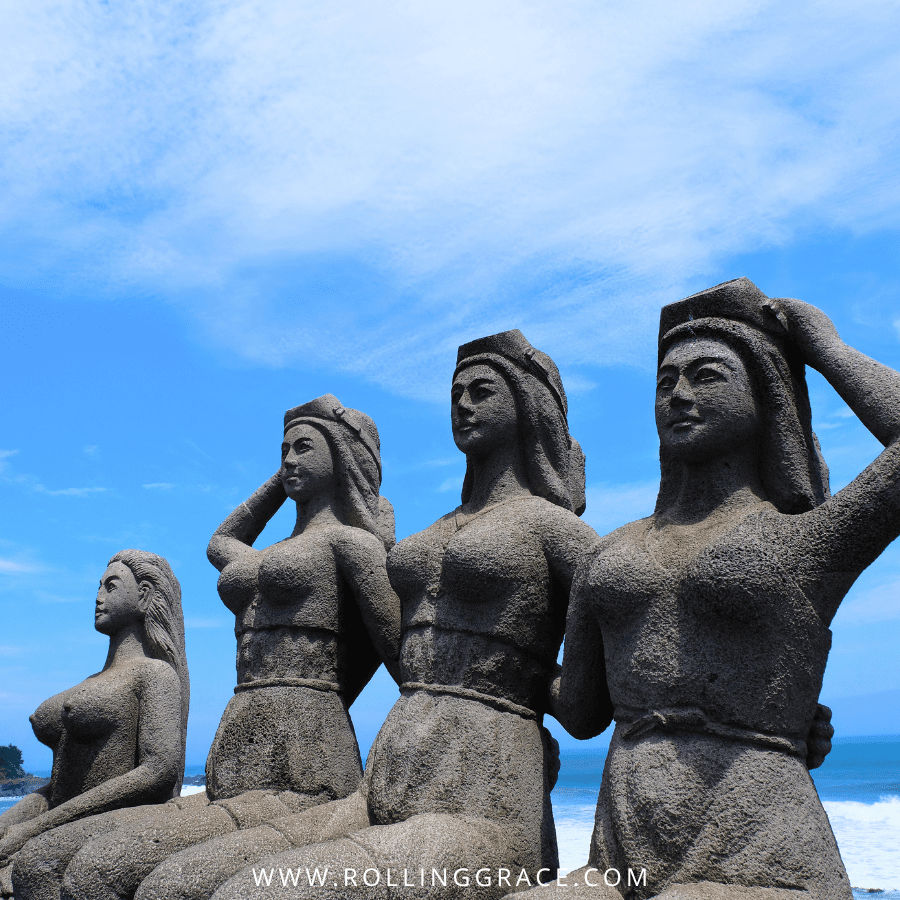 Bronze haenyeo statues on the rocky coastline of Jeju Island, South Korea.
