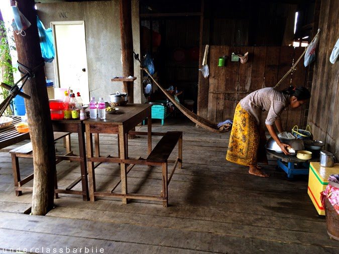1-Day Kampong Khleang Itinerary: Best Attractions & Tips 15 Interior of a stilt house at Kampong Khleang floating village, Cambodia, with a villager in the background.