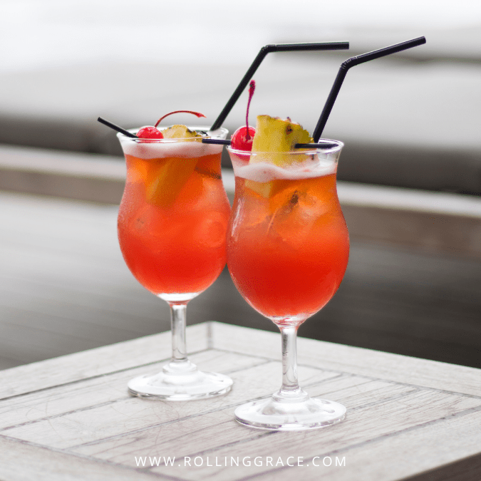 Two Singapore Sling cocktails garnished with pineapple and cherry in tall glasses.