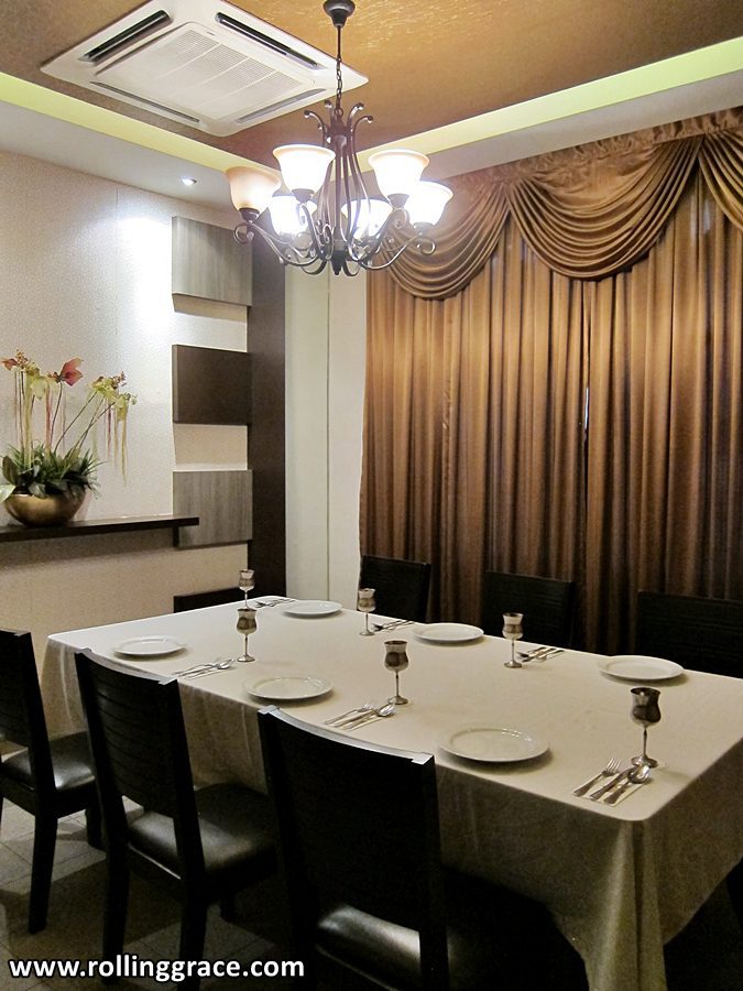 Elegant main dining hall at Tandoor Grill Ipoh in Greentown with white table settings and chandelier lighting.