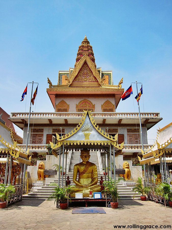 Wat Ounalom pagoda entrance with golden Buddha statue and red-roofed hall, Phnom Penh, Cambodia