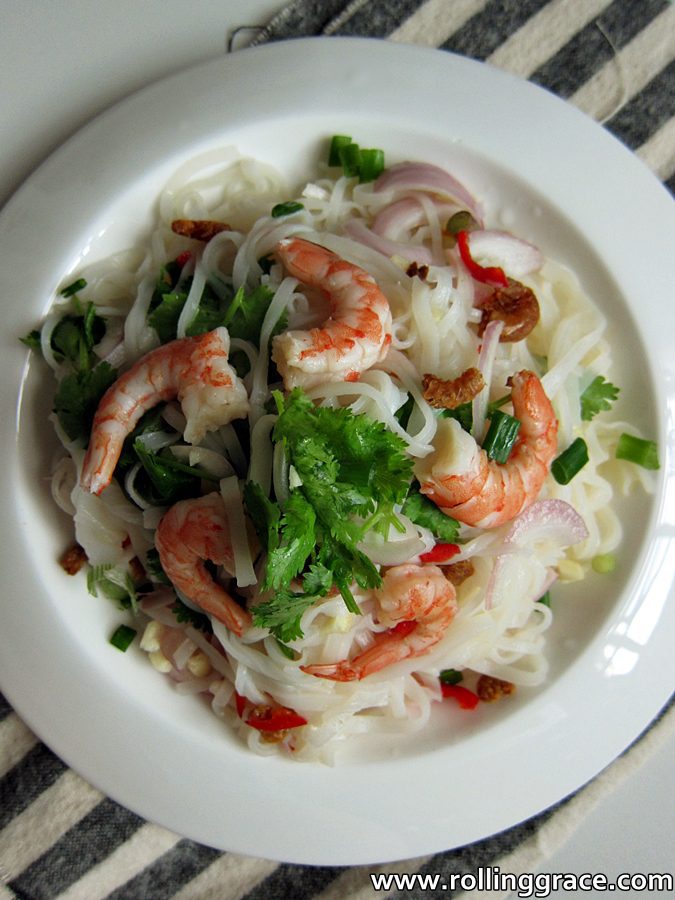 Yum Sen Mee Thai spicy noodle salad with poached shrimp and fresh herbs, shot from above on a white plate.