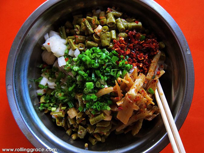 Bowl of Guilin Rice Noodles topped with scallions, chilli flakes and pickled vegetables