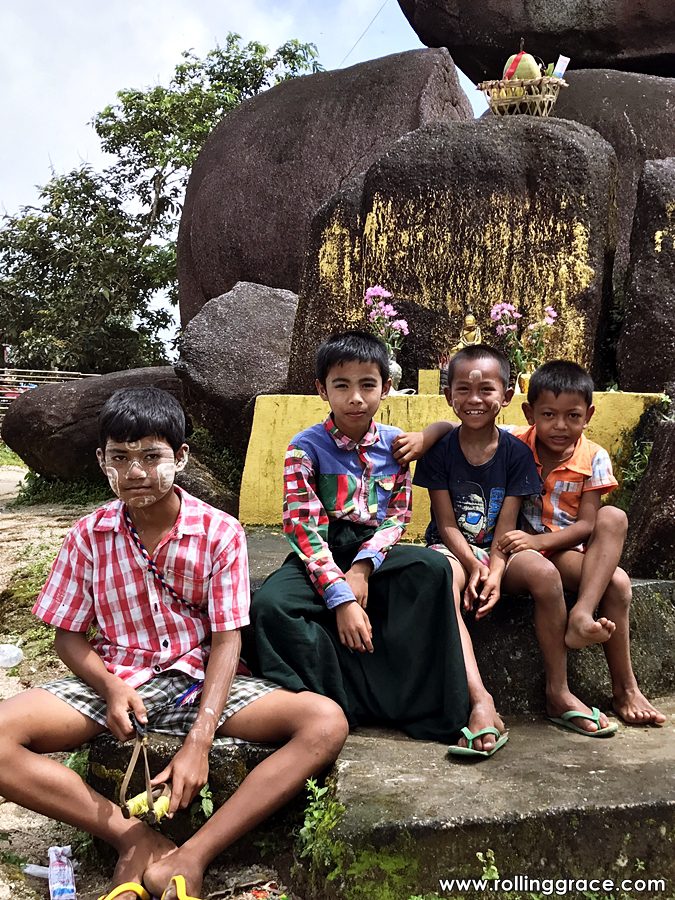 Burmese children wearing thanaka on their faces seated at a temple in Myanmar