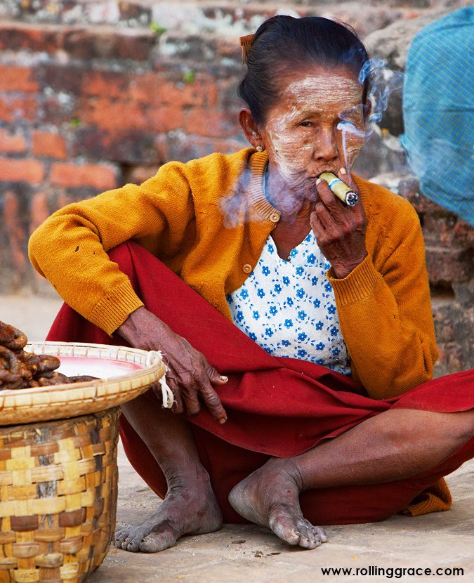 Elderly Burmese woman wearing thanaka and smoking a cheroot cigar in Myanmar