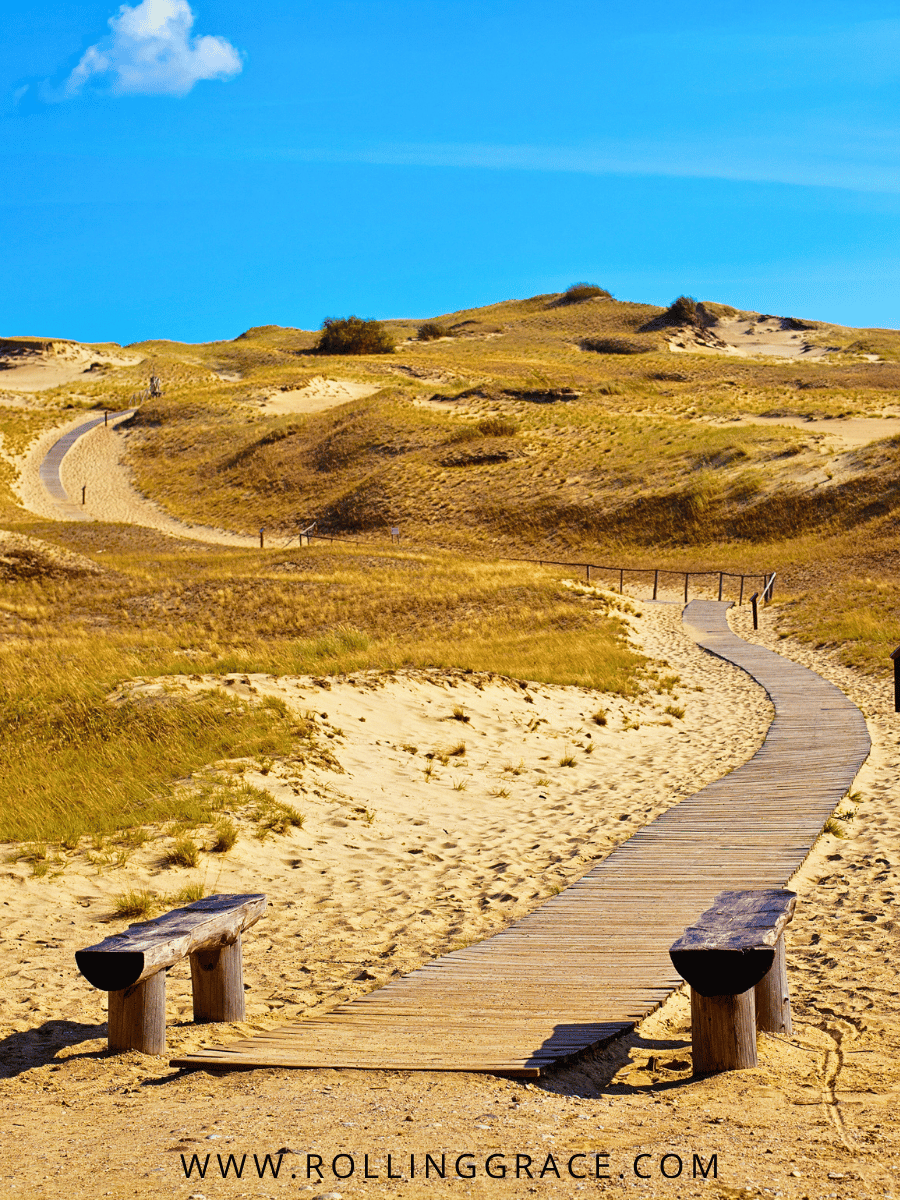 Exploring Curonian Spit Lithuania: 10 Amazing Things to Do 6 Wooden boardwalk winding through sand dunes with a view of the Baltic Sea on the Curonian Spit Lithuania