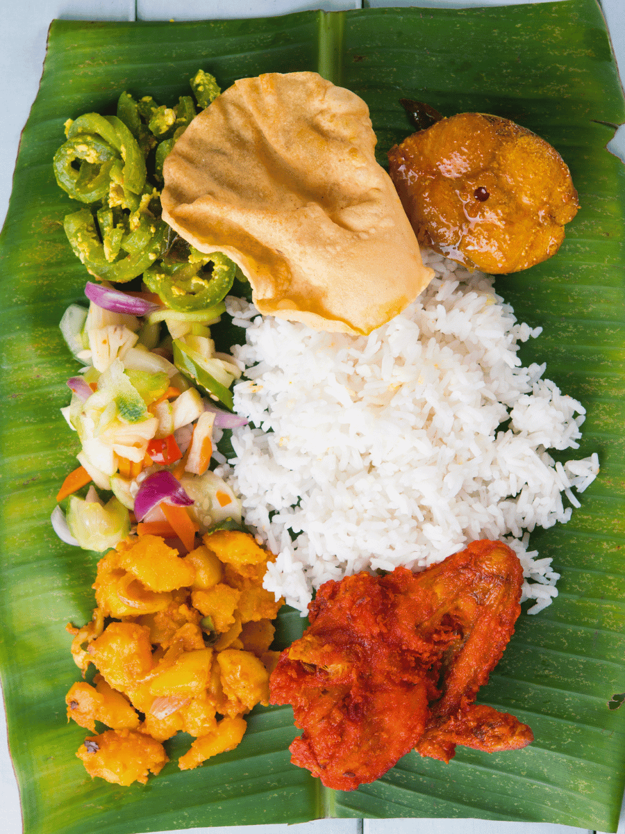 Banana leaf rice with white rice fried chicken and curries served on a banana leaf, a South Indian Malaysian rice dish