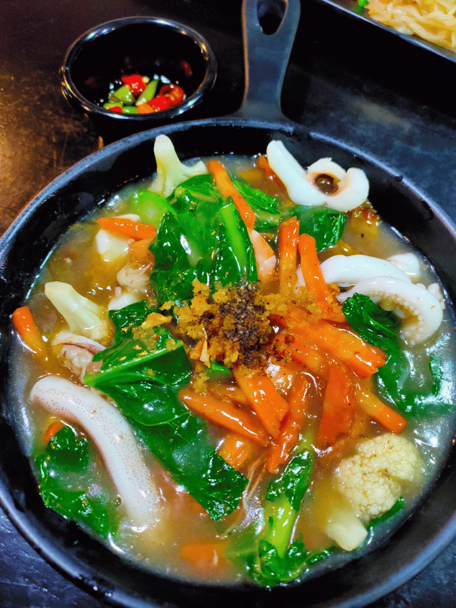 Nasi goreng ladna with thick gravy vegetables and protein in a dark bowl, a popular Malaysian rice dish