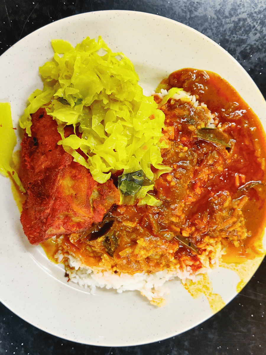 Nasi kandar white rice with multiple curries and fried chicken on a plate, a Penang-origin Malaysian rice dish