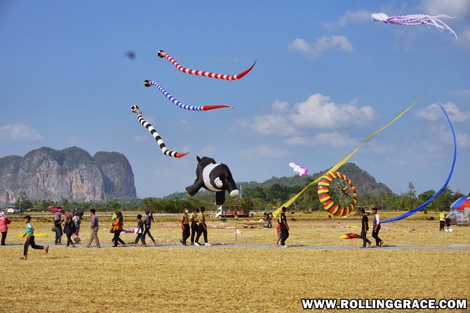 Kite fliers on open fields with hills behind at Pesta Angin Timur Perlis Malaysia