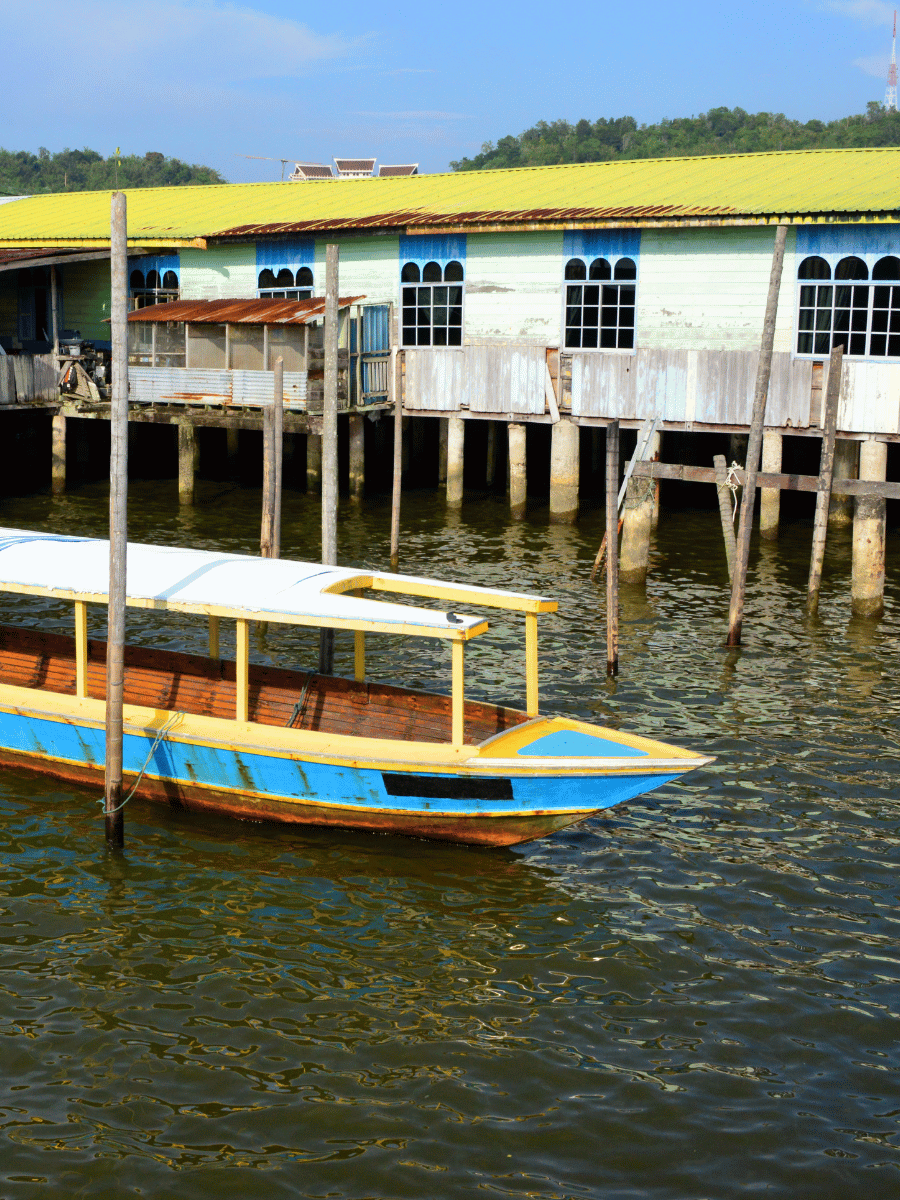 7 Best Things to Do at Kampong Ayer Brunei Water Village 6 Water taxis with yellow and blue hulls docked beside stilt houses on the Brunei River at Kampong Ayer Brunei
