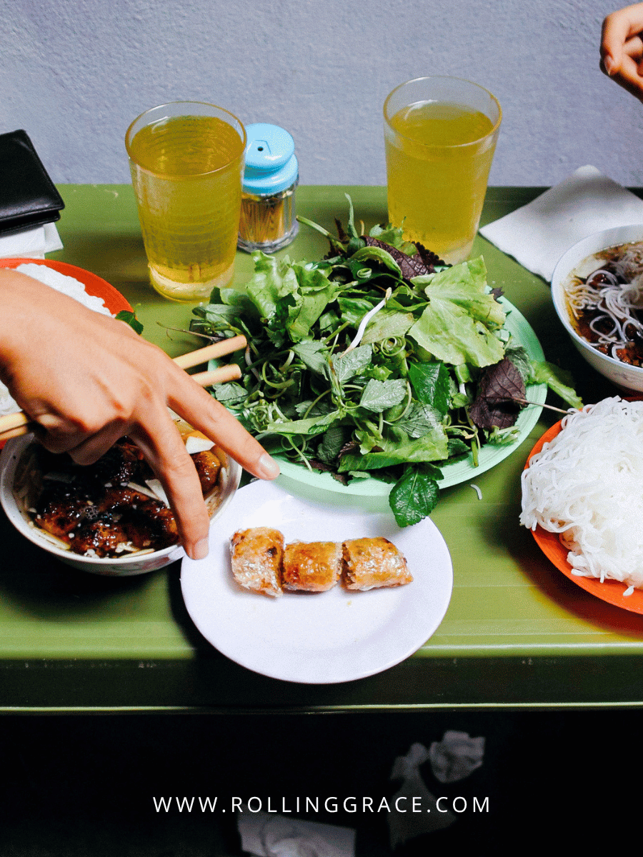 Spring rolls and local Vietnamese dishes served with fresh herbs and beer in Hanoi Old Quarter