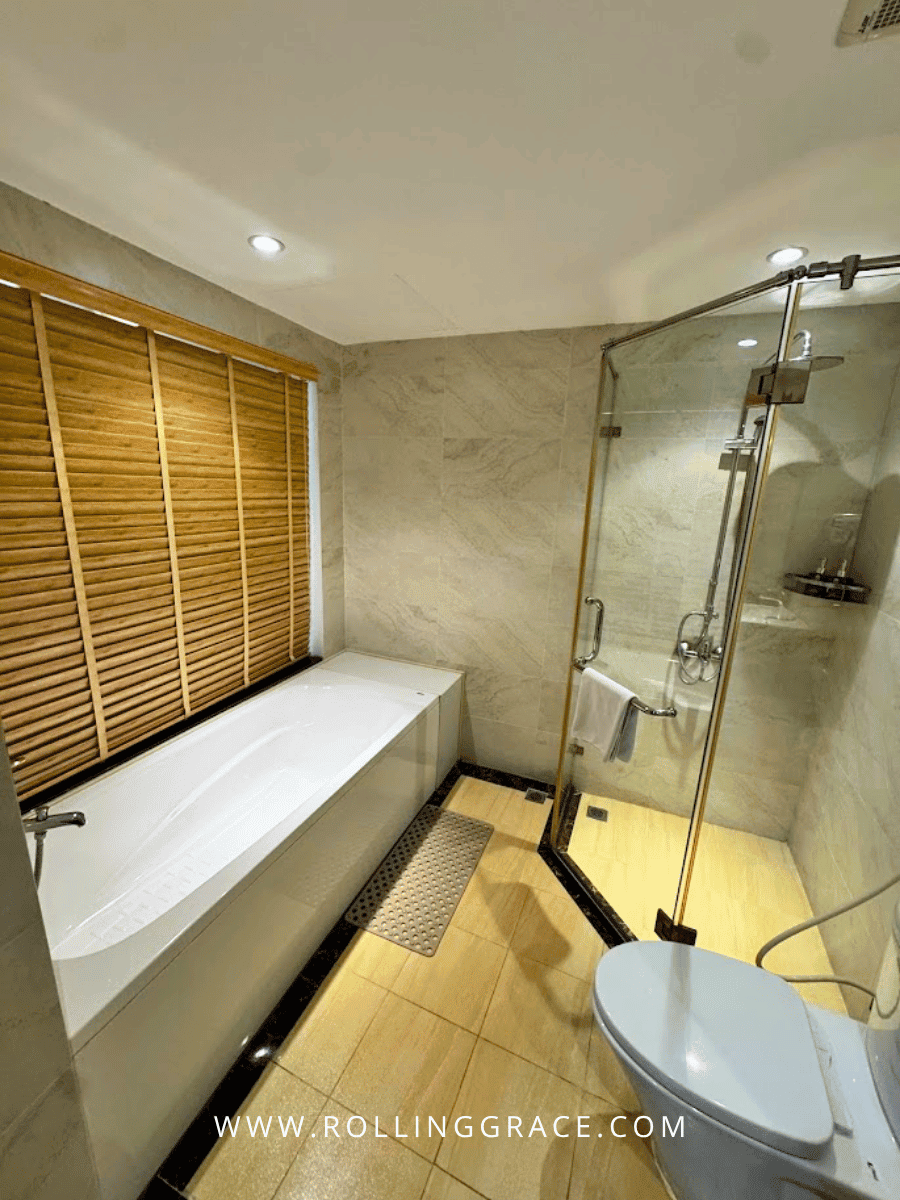Bathroom with glass-enclosed bathtub and rain shower in Junior Suite at Minasi Grand Hotel Hanoi