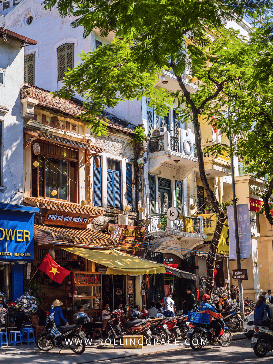 Colourful buildings and motorbikes lining a narrow street in Hanoi Old Quarter Vietnam