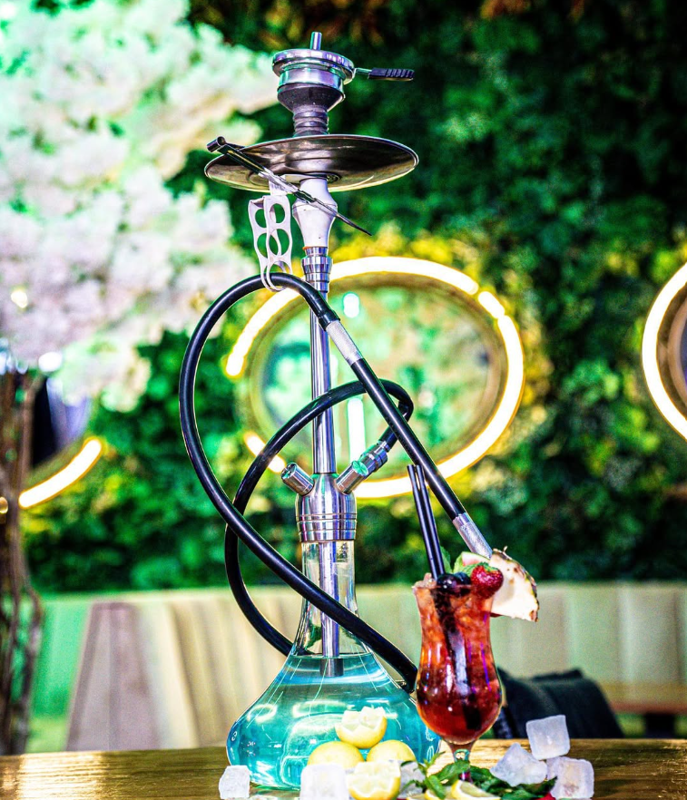 Kleopatra Shisha Bar Berlin Mitte with decorative hookah pipe and green neon-lit garden setting